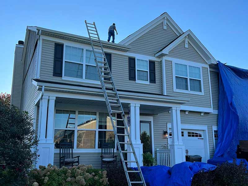 Mid-class, two-story beige home in the process of getting a roof replacement by Casgo Roofing
