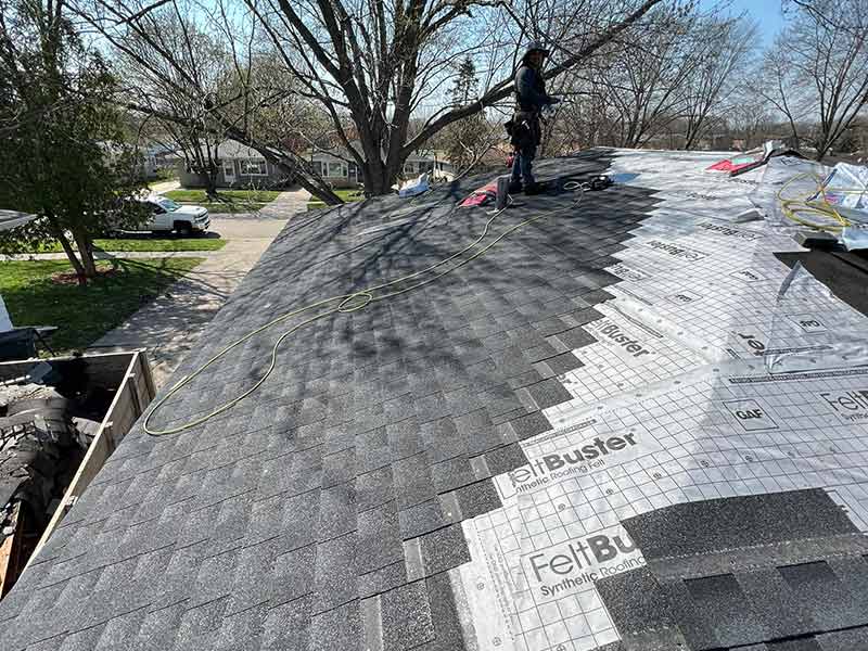 Casgo Roofing crew member installing new gray shingles on a residential roof